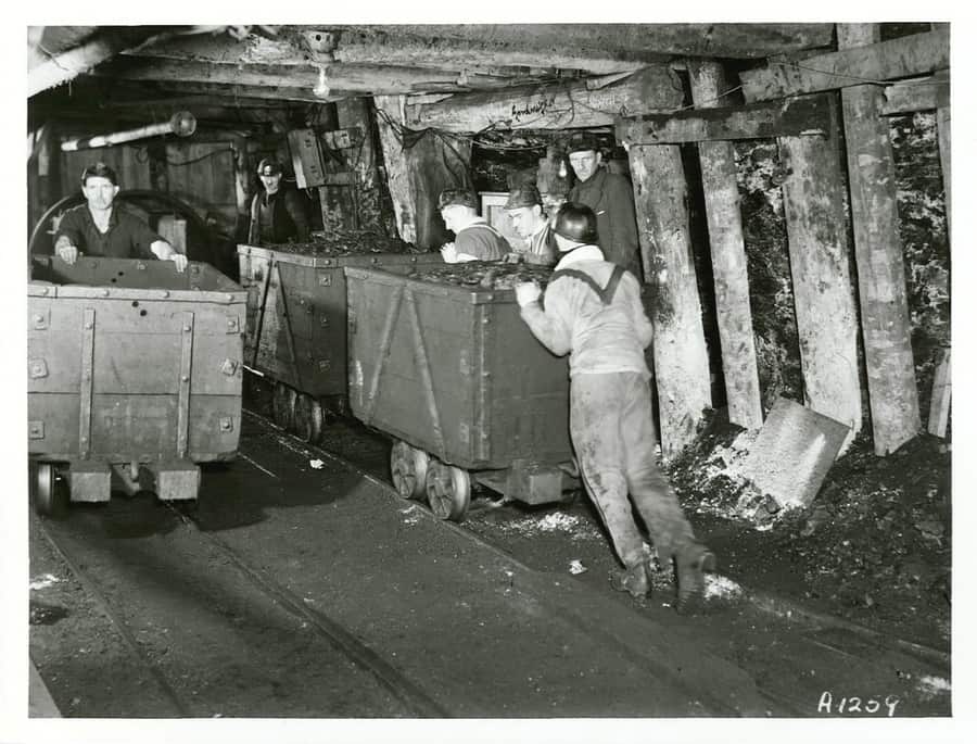 Coal miners pushing coal trucks in a mine in Blackball, Westland